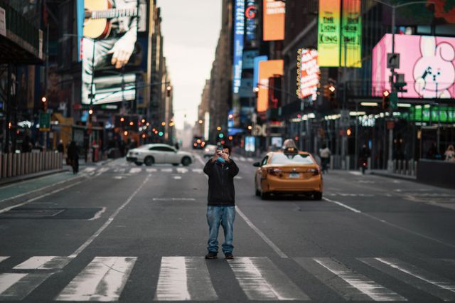 A photo of a man standing in the middle of empty Times Square taking a photo